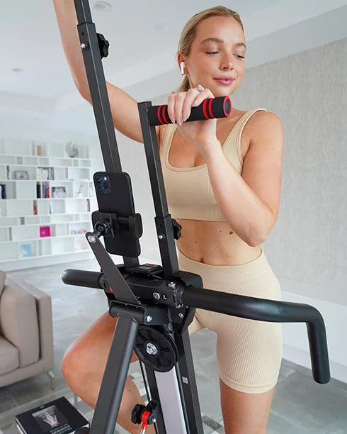MaxiClimber - Perfect for all fitness levels / Young blond woman working out on the MaxiClimber XL using her mobile for the MaxiClimber Fitness App