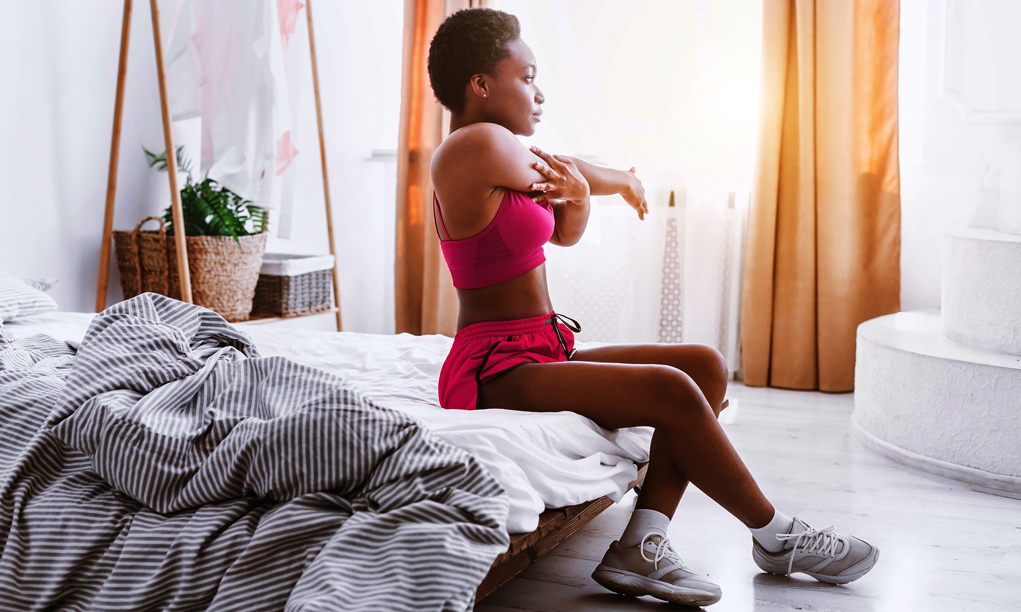 Young woman sitting in bed stretching before her early workout