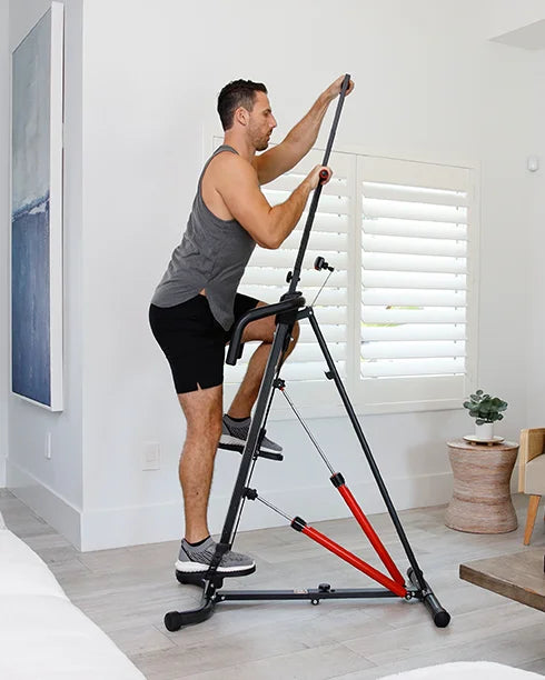 MaxiClimber- Lose weight with maximum movement / Young man dressedin gray shirt and black shorts on the MaxiClimber XL working out in his living room