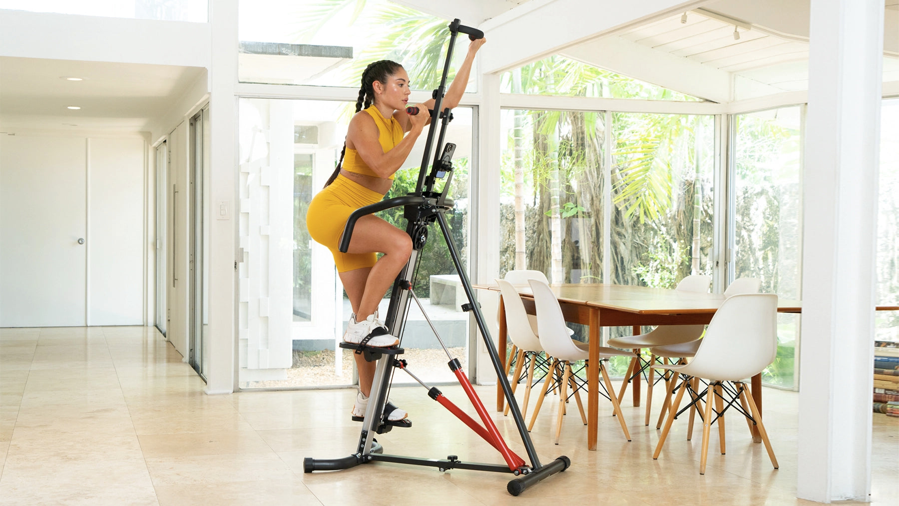 MaxiClimber XL 2000 deatures a 12-level Hydraulic Resistance System / Brunette wearing yellow working out on the MaxiClimber XL 2000 in a dining room