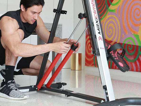 MaxiClimber XL 2000 features a 12-level Hydraulic Piston Resistance / Young man wearing a black shirt adjusting the resistance pistons of the MaxiClimber XL 2000